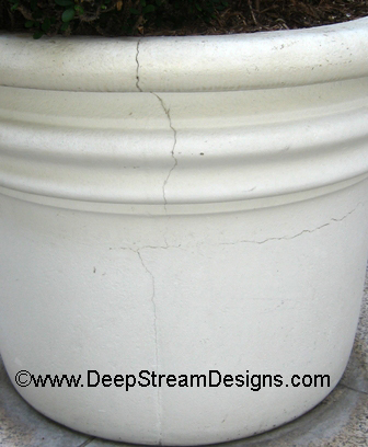 close up photo of a large white concrete planter with a vertical crack.
